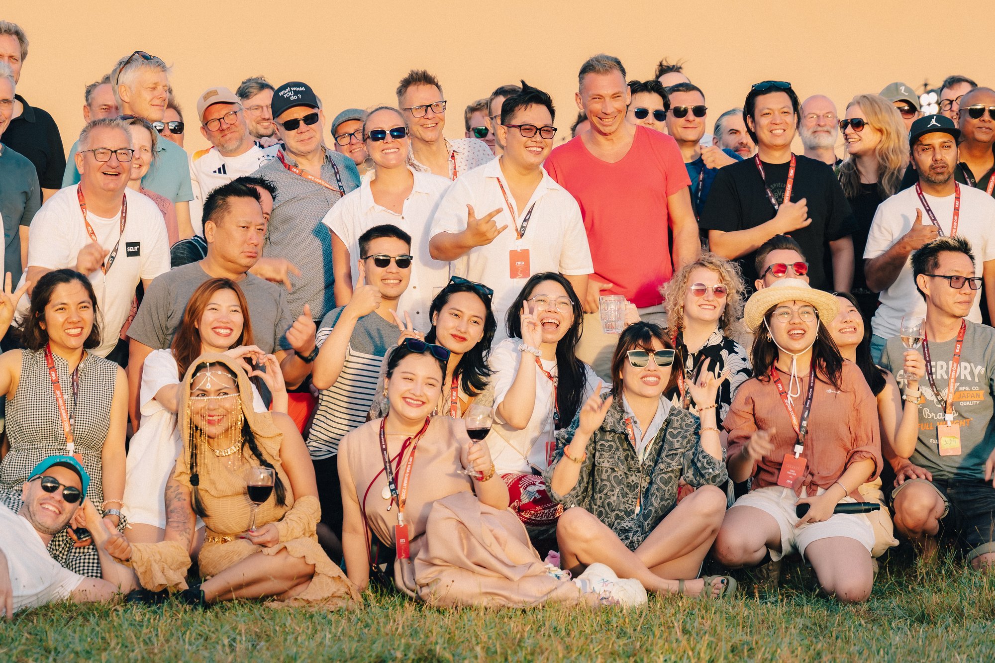 Group picture of a smiling event team in a summery and easy setting standing in front of an orange wall.