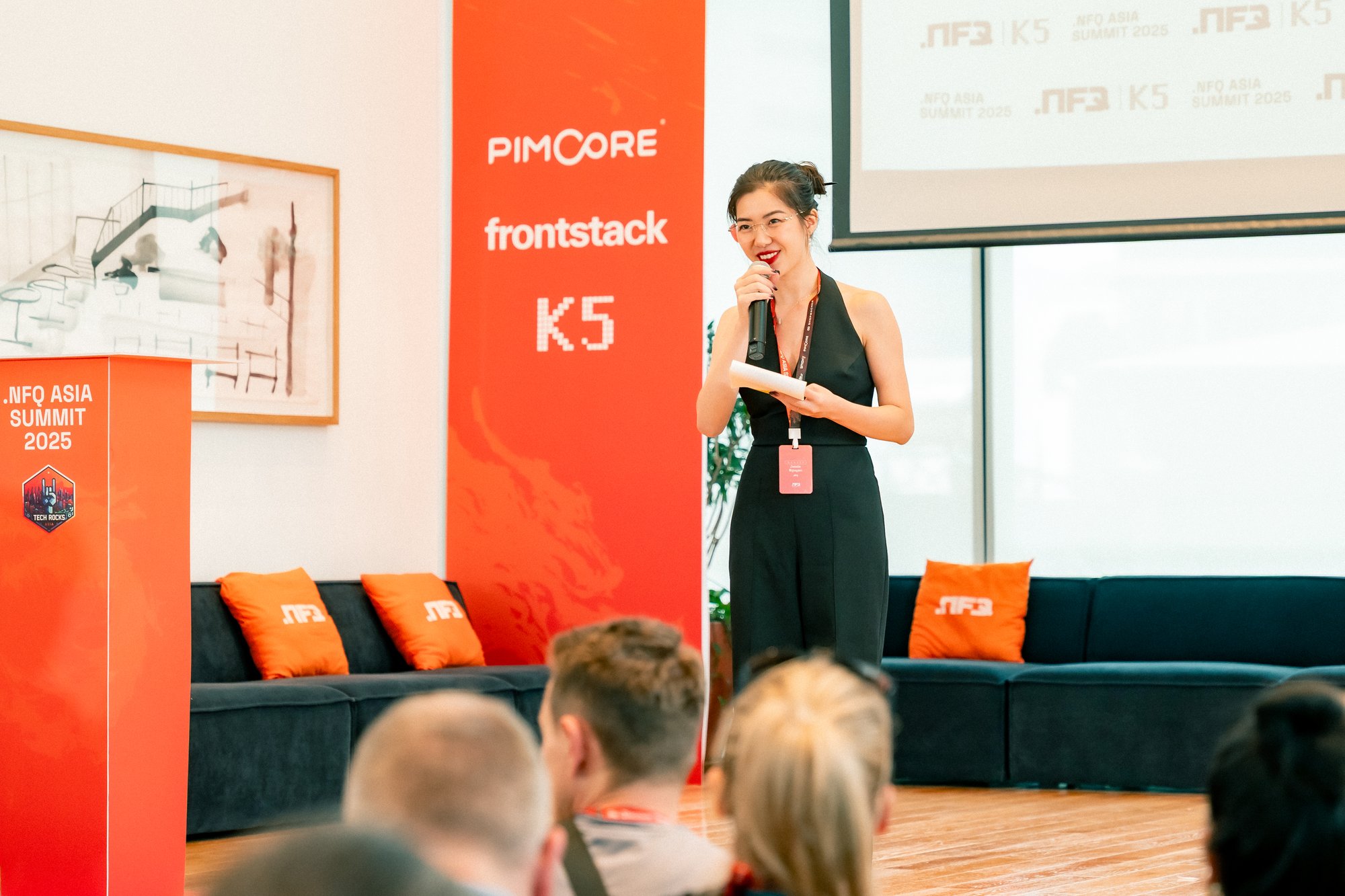 Presenter, presenting on a branded Stage in a bright presenting room.